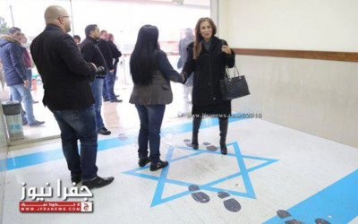 Jordan's minister for media affairs and communications and government spokesperson, Jumana Ghunaimat (R), stepping on the Israeli flag at the entrance to the trade union headquarters in Amman, December 2018. (Screen capture: Jamuna TV)