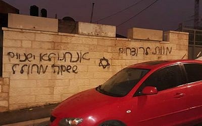 A car in the East Jerusalem of Beit Hanina whose tires were slashed next to a wall that was gratified with a Jewish star the Hebrew phrases "Death to murderers" and "We don't sleep when the name of God is desecrated" on December 20, 2018. (Courtesy)