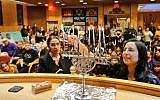 Alexandria Ocasio-Cortez (L) helps light a candle at a Hannukah celebration on December 9, 2018 ( Jews for Racial & Economic Justice/Twitter)