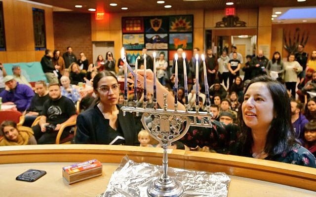 Alexandria Ocasio-Cortez (L) helps light a candle at a Hannukah celebration on December 9, 2018 ( Jews for Racial & Economic Justice/Twitter) Alexandria Ocasio-Cortez (L) helps light a candle at a Hannukah celebration on December 9, 2018 ( Jews for Racial & Economic Justice/Twitter)