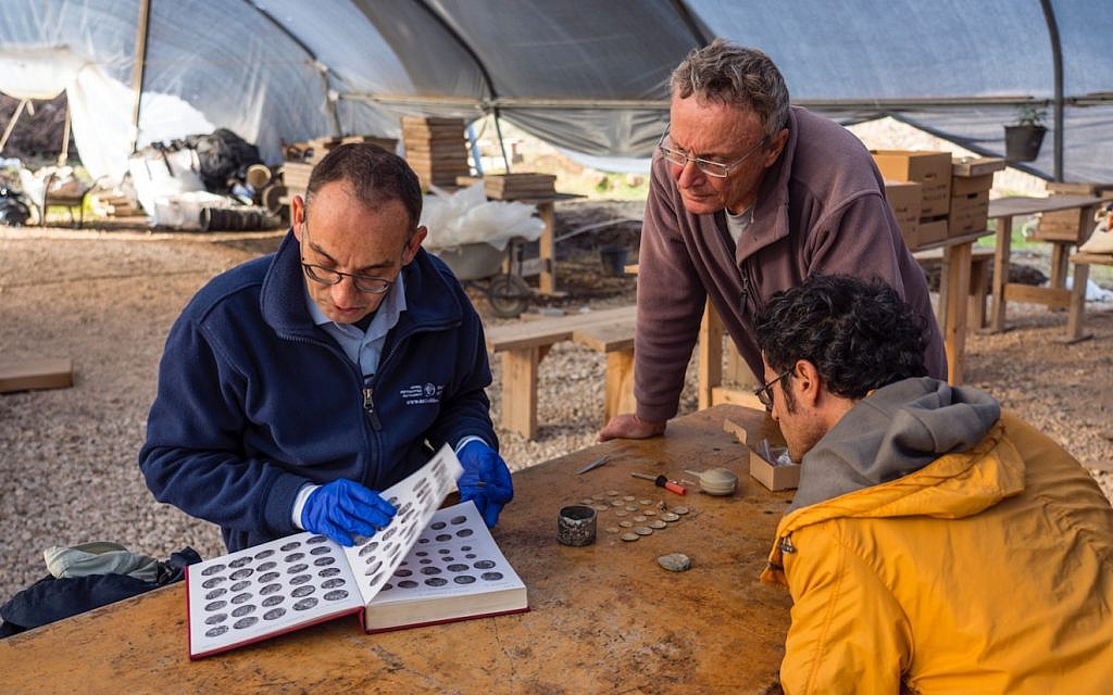 Preliminary identification of the coins discovered at the Caesarea Maritima archaeological site by (left) Dr. Robert Kool, coin expert at the Israel Antiquities Authority, and (standing) dig co-director Dr. Peter Gendelman. (Yaniv Berman, courtesy of the Caesarea Development Corporation)