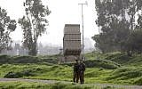 Illustrative: Israeli soldiers stand near a battery of the Iron Dome missile defense system deployed in Tel Aviv on January 24, 2019. (Menahem Kahana/AFP)