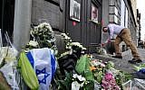 File: A man lays flowers as he pays his respects in front of a makeshift memorial at the entrance of the Jewish Museum in Brussels, where a deadly shooting took place the day before, killing four, May 25, 2014 (Georges Gobet/AFP)