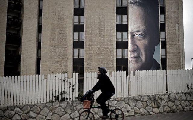 A man rides a bycicle past a political campaign poster of former IDF chief of staff Benny Gantz, in Jerusalem, on January 28, 2019. (THOMAS COEX / AFP) A man rides a bycicle past a political campaign poster of former IDF chief of staff Benny Gantz, in Jerusalem, on January 28, 2019. (THOMAS COEX / AFP)