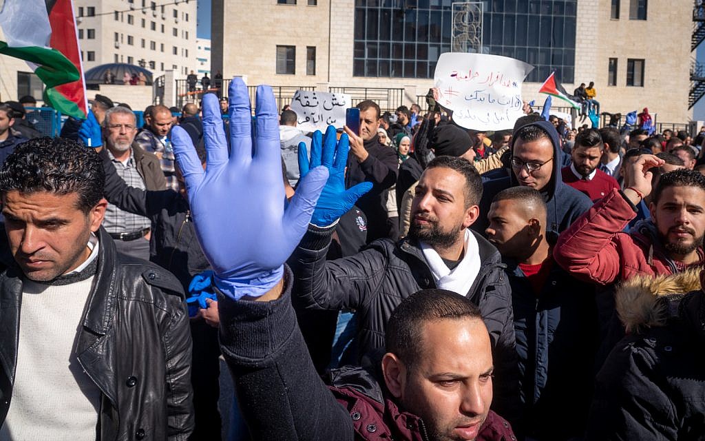 Palestinians protest against a government tax hike in Ramallah, West Bank, December 12, 2018. The blue gloves are a unifying symbol for the protesters, compared to the yellow vests worn by protesters in recent demonstrations in France. (Luke Tress/Times of Israel)