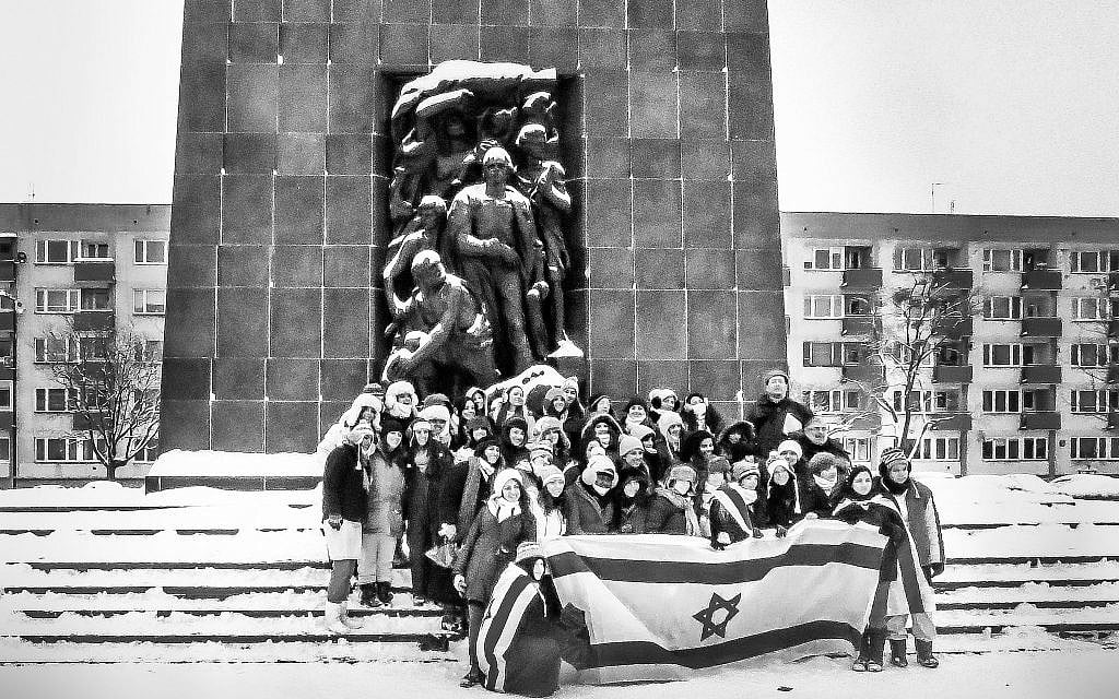 A group of Israeli school children, accompanied by an armed guard, pose with an Israeli flag before Natan Rapoport’s 1948 Monument to the Ghetto Heroes to memorialize their visit and mark its meaning for the Israeli state. (Courtesy Walkowitz)