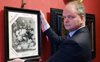 In this photo made available on January 1, 2019, Eike Schmidt, director of the Uffizi Gallery, poses for a photo as he holds onto a copy of a still-life "Vase of Flowers," by Dutch artist Jan van Huysum, with writing in red reading "stolen," inside the Uffizi gallery, in Florence, Italy. (Uffizi Gallery press office via AP)