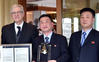 This March 20, 2018 photo made available Thursday, January 3, 2019 by the Parish of Farra di Soligo, Italy, shows North Korea's acting ambassador to Italy Jo Song Gil, center, holding a model of "Bell of Peace of Rovereto" during a cultural event on the occasion of a visit of the North Korean delegation to the Veneto region, in San Pietro di Feletto, near Treviso, northern Italy. Jo Song Gil is flanked by Senator Valentino Perin, left, and an unidentified North Korean diplomat at right. (Parish of Farra di Soligo via AP)