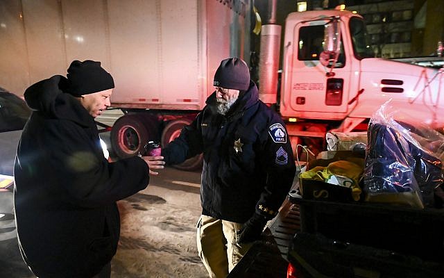 Minneapolis Police Sgt. Grant Snyder, right, hands a cup of hot chocolate to Dawone Boclair outside the public library on Hennepin Avenue in downtown Minneapolis, Minnesota, as temperatures dip well below freezing, Tuesday, January 29, 2019. (Aaron Lavinsky/Star Tribune via AP) Minneapolis Police Sgt. Grant Snyder, right, hands a cup of hot chocolate to Dawone Boclair outside the public library on Hennepin Avenue in downtown Minneapolis, Minnesota, as temperatures dip well below freezing, Tuesday, January 29, 2019. (Aaron Lavinsky/Star Tribune via AP)