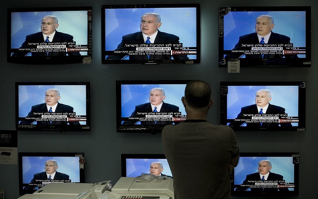 Illustrative: A man watches Prime Minister Benjamin Netanyahu making a speech on television screens at a shop in Jerusalem, on June 14, 2009. (AP/Bernat Armangue/File)
