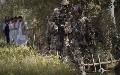 Afghan men watch German Army soldiers patroling near Char Darah, outside Kunduz, Afghanistan, September 20, 2011. (Anja Niedringhaus/AP)