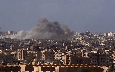 File: Smoke and debris rising after Syrian government shelling of the city of Deir el-Zour during a battle against Islamic State in 2017 (SANA via AP)