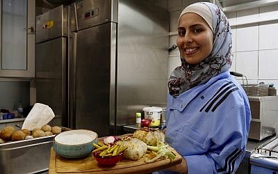 In this photo from November 9, 2018, Malakeh Jazmati carries food in her restaurant in Berlin, Germany. (AP Photo/Jona Kallgren)