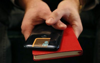 John Scott-Railton, a senior researcher at the Citizen Lab, an internet watchdog group, holds his cell phone which has its camera blocked by an adhesive sticker, as he poses for a photograph on Jan. 17, 2019, in New York. (AP Photo/Kathy Willens)