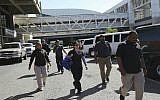 United States embassy security agents walk after dropping off US embassy employees and their families at the Simon Bolivar international airport in La Guaira, Venezuela, Friday, Jan. 25, 2018. (AP/Rodrigo Abd)