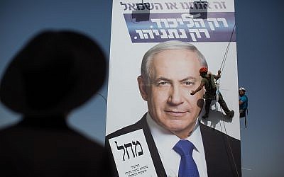 File: An ultra-Orthodox man looks at workers hanging a Likud campaign poster featuring Prime Minister Benjamin Netanyahu at the entrance to Jerusalem on March 11, 2015 in Jerusalem. (Yonatan Sindel/Flash90)