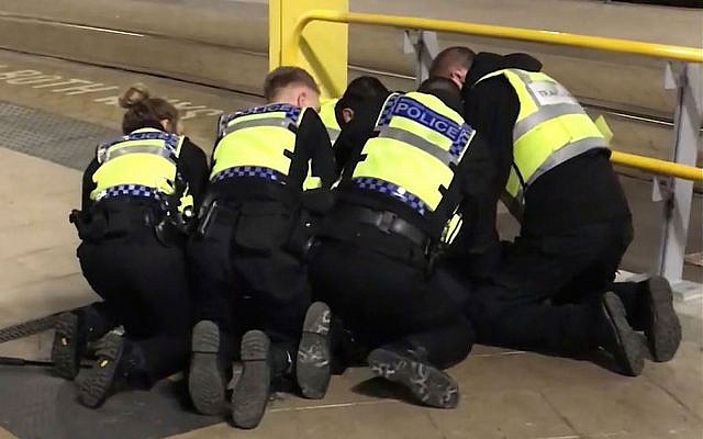 Police restrain a man after he stabbed three people at Victoria Station in Manchester, England, late Monday Dec. 31, 2018. Two commuters - a man and woman in their 50s - were taken to hospital with knife injuries and a British Transport Police (BTP) officer was stabbed in the shoulder. Police said a man was arrested on suspicion of attempted murder and remains in custody. (Sam Clack/PA via AP) Police restrain a man after he stabbed three people at Victoria Station in Manchester, England, late Monday Dec. 31, 2018. Two commuters - a man and woman in their 50s - were taken to hospital with knife injuries and a British Transport Police (BTP) officer was stabbed in the shoulder. Police said a man was arrested on suspicion of attempted murder and remains in custody. (Sam Clack/PA via AP)