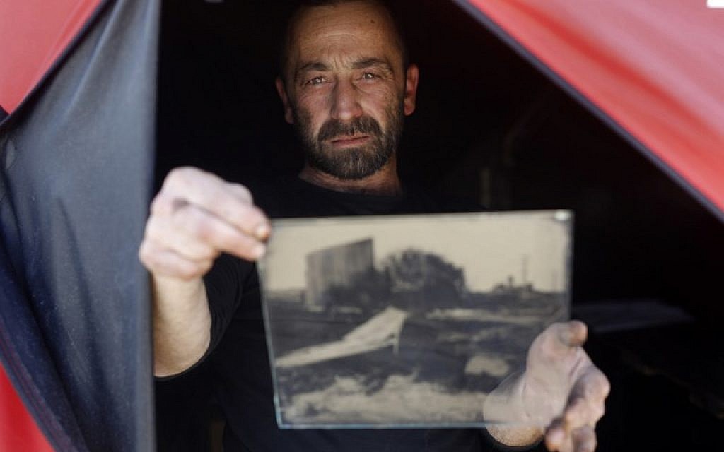 Edward Kaprov, an Israeli photographer, holds one of his images on a glass plate in his field darkroom, near Kibbutz Kissufim, overlooking the northern Gaza border, on February 5, 2019. (Menahem Kahana/AFP) Edward Kaprov, an Israeli photographer, holds one of his images on a glass plate in his field darkroom, near Kibbutz Kissufim, overlooking the northern Gaza border, on February 5, 2019. (Menahem Kahana/AFP)