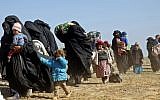 Women and children fleeing the battered Islamic State-held holdout of Baghouz in the eastern Syrian province of Deir Ezzor walk with covers and suitcases into a nearby area held by the Syrian Democratic Forces (SDF), on February 12, 2019. (Delil souleiman/AFP)