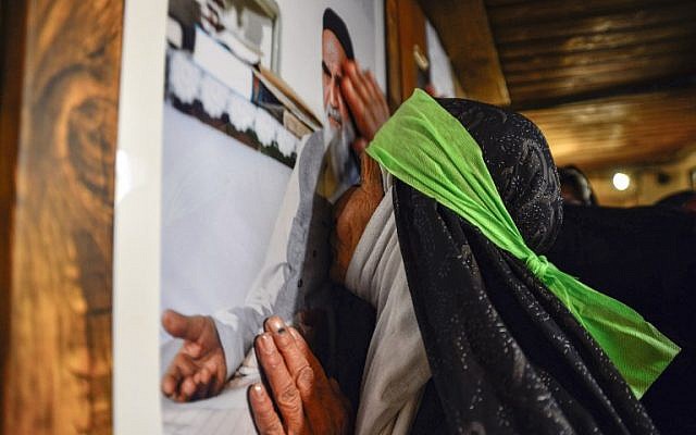 An Iranian woman kisses a portrait of Islamic Revolution leader Ayatollah Ruhollah Khomeini, as she visits the house where he lived during his 13-year-exile in Iraq, along al-Rasul street near the shrine of Imam Ali in the central holy city of Najaf on February 13, 2019, while marking the 40th anniversary of the Islamic Revolution in Iran. (Haidar HAMDANI / AFP)