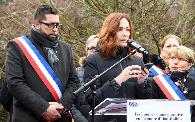 Sainte-Genevieve-des-Bois mayor Frederic Petitta, left, listens to a speech by French writer Emilie Freche, on February 13, 2019 in Sainte-Genevieve-des-Bois, at a ceremony honoring Ilan Halimi, two days after two trees planted in memory of the 23-year-old Jewish man abducted and killed over a decade ago by an anti-Semitic gang were found vandalized. (Bertrand Guay/AFP) Sainte-Genevieve-des-Bois mayor Frederic Petitta, left, listens to a speech by French writer Emilie Freche, on February 13, 2019 in Sainte-Genevieve-des-Bois, at a ceremony honoring Ilan Halimi, two days after two trees planted in memory of the 23-year-old Jewish man abducted and killed over a decade ago by an anti-Semitic gang were found vandalized. (Bertrand Guay/AFP)