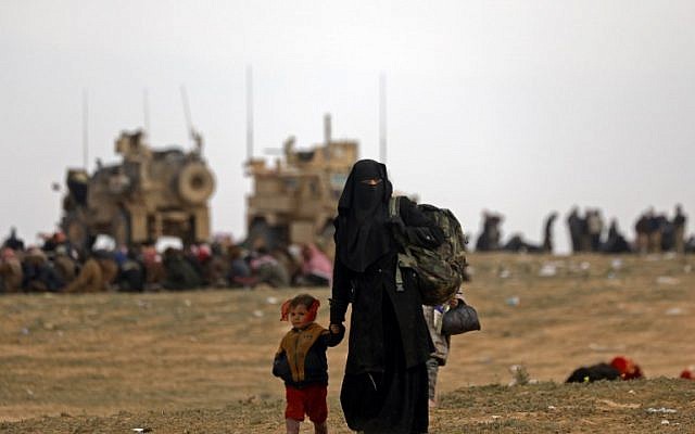 Civilians fleeing the Islamic State's group embattled holdout of Baghouz walk in a field on February 13, 2019. (Delil Souleiman/AFP) Civilians fleeing the Islamic State's group embattled holdout of Baghouz walk in a field on February 13, 2019. (Delil Souleiman/AFP)