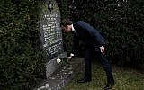 French President Emmanuel Macron lays a white rose on a grave vandalized with swastikas during a visit at the Jewish cemetery in Quatzenheim, on February 19, 2019, on the day of a nationwide marches against a rise in anti-Semitic attacks. (Frederick Florin/ Pool/ AFP)