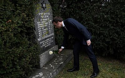 French President Emmanuel Macron lays a white rose on a grave vandalized with swastikas during a visit at the Jewish cemetery in Quatzenheim, on February 19, 2019, on the day of a nationwide marches against a rise in anti-Semitic attacks. (Frederick Florin/ Pool/ AFP)