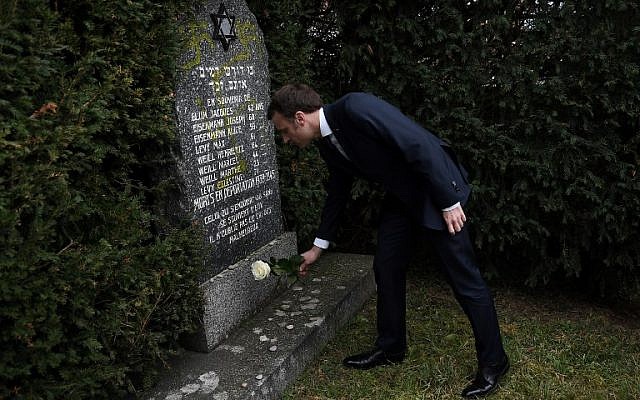 French President Emmanuel Macron lays a white rose on a grave vandalized with swastikas during a visit at the Jewish cemetery in Quatzenheim, on February 19, 2019, on the day of a nationwide marches against a rise in anti-Semitic attacks. (Frederick Florin/ Pool/ AFP) French President Emmanuel Macron lays a white rose on a grave vandalized with swastikas during a visit at the Jewish cemetery in Quatzenheim, on February 19, 2019, on the day of a nationwide marches against a rise in anti-Semitic attacks. (Frederick Florin/ Pool/ AFP)