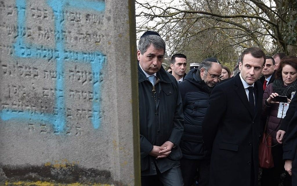 Illustrative: French President Emmanuel Macron looks at a grave vandalized with a swastika during a visit at the Jewish cemetery in Quatzenheim, on February 19, 2019, on the day of nationwide marches against a rise in anti-Semitic attacks. (Frederick Florin/Pool/AFP) Illustrative: French President Emmanuel Macron looks at a grave vandalized with a swastika during a visit at the Jewish cemetery in Quatzenheim, on February 19, 2019, on the day of nationwide marches against a rise in anti-Semitic attacks. (Frederick Florin/Pool/AFP)