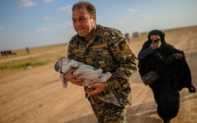 Mostapha Bali, the spokesman for the Kurdish-led Syrian Democratic Forces (SDF), carries a baby followed by a woman after fleeing the Islamic State (IS) group's last holdout of Baghouz, in Syria's northern Deir Ezzor province, on February 22, 2019. (Bulent KILIC / AFP) Mostapha Bali, the spokesman for the Kurdish-led Syrian Democratic Forces (SDF), carries a baby followed by a woman after fleeing the Islamic State (IS) group's last holdout of Baghouz, in Syria's northern Deir Ezzor province, on February 22, 2019. (Bulent KILIC / AFP)