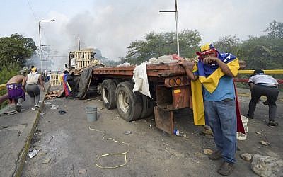 Demonstrators duck behind a truck during clashes with the security forces at the Francisco de Paula Santander international bridge Bridge linking Cucuta, Colombia, and Urena, Venezuela, during an attempt to cross humanitarian aid over the border into Venezuela, on February 23, 2019. (RAUL ARBOLEDA / AFP)