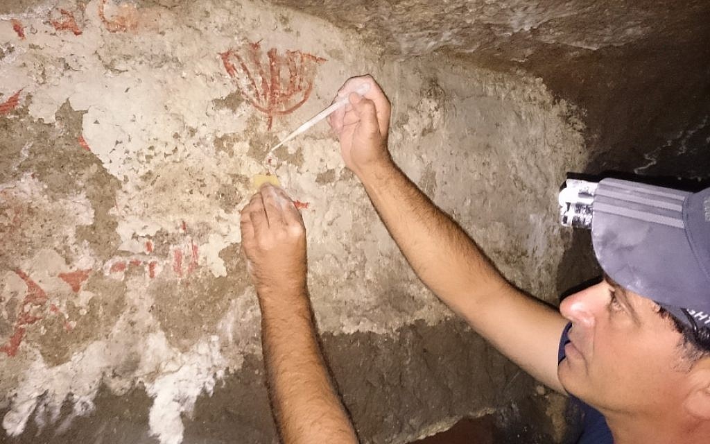 Amir Genach working to conserve the depiction of a menorah (courtesy Amir Genach)