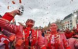 Revellers in a red spotlight celebrate the start of the carnival season in the streets of Cologne, Germany, Nov. 11, 2018. (AP Photo/Martin Meissner)