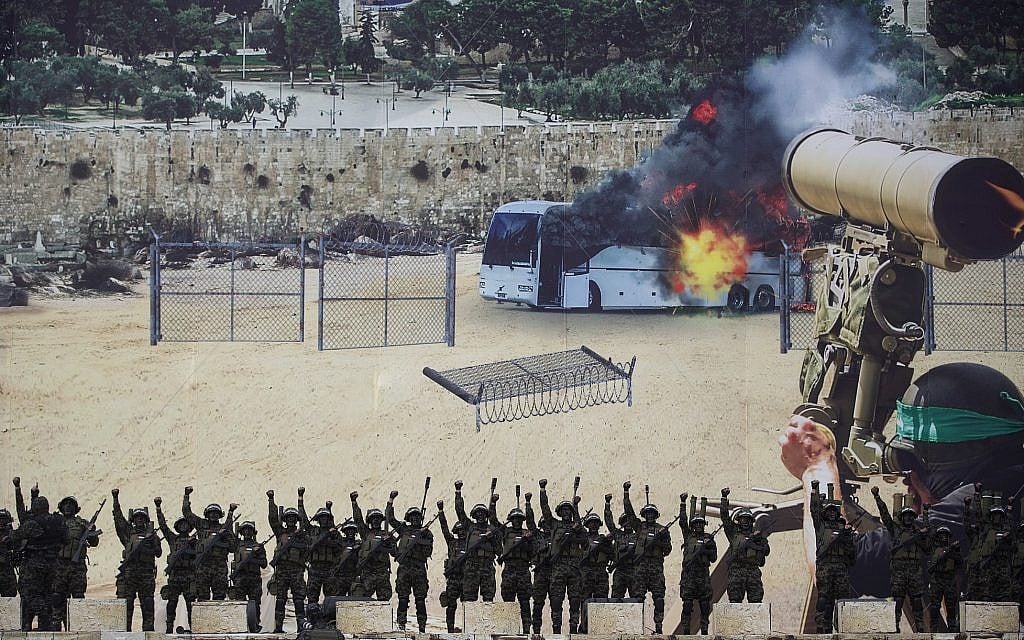 Masked gunmen of the al-Qassam brigades, the military wing of Hamas, raise their hands as they stand in front of a huge poster showing a mock attack on a bus, during a mass rally in Gaza, December 16, 2018. (Khalil Hamra/AP)