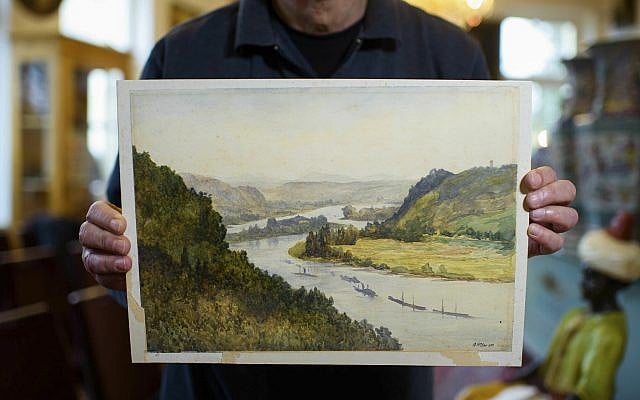 An employee of an action house holds a watercolor landscape, allegedly painted by a young Adolf Hitler but of uncertain origin, in Berlin, Germany, January 24, 2019. (Gregor Fischer/dpa via AP)