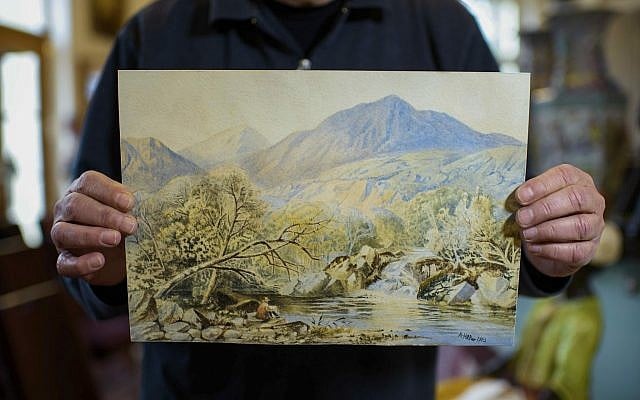 An employee of an action house holds a watercolor landscape, allegedly painted by a young Adolf Hitler, in Berlin, Germany, January 24, 2019. (Gregor Fischer/dpa via AP)