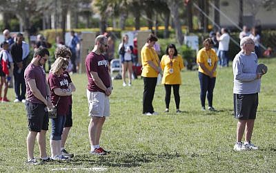 People at Trails End Park pause for a moment of silence in honor of the 17 that were killed during the Marjory Stoneman Douglas High School shooting last year, Thursday, Feb. 14, 2019, in Parkland, Fla. (AP/Wilfredo Lee)
