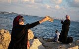 Women use their phones in the Old City of Acre, in northern Israel, August 1, 2018.(David Cohen/Flash90)
