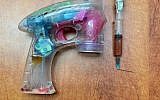 A soap bubble gun and syringe allegedly used by a Jordanian citizen to hold up an Israeli postal bank in January 2019. (Israel Police)