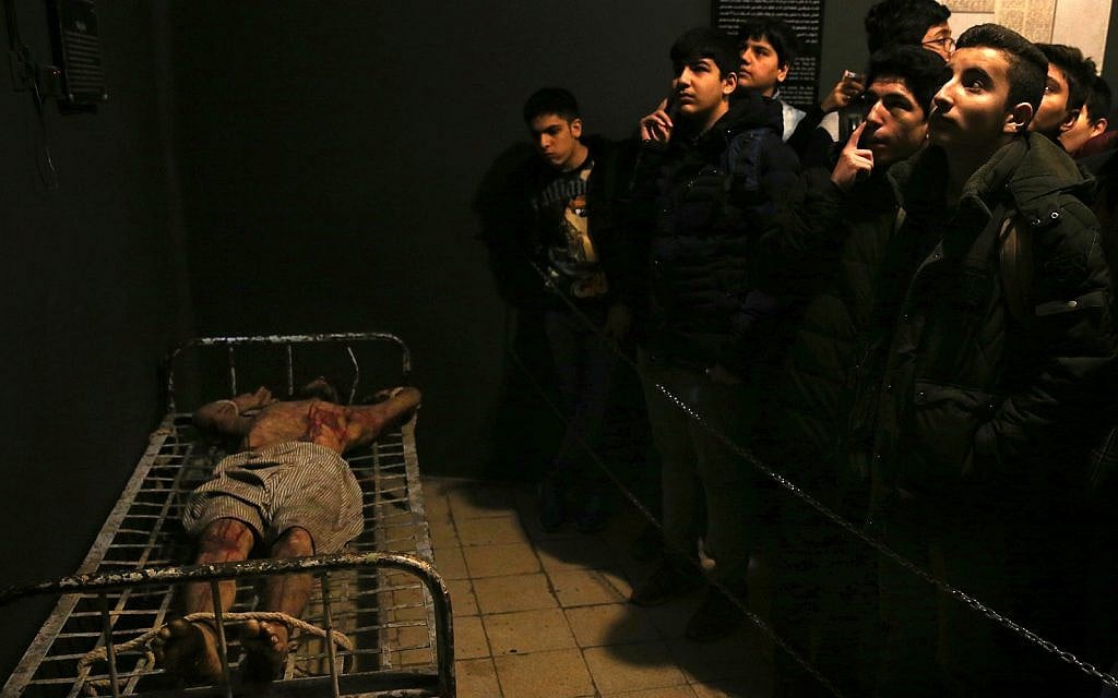 Iranian schoolboys look at an exhibition at a former prison run by the pre-revolution intelligence service, SAVAK, now a museum, where a wax mannequin of a prisoner is tied to a bed, in downtown Tehran, Iran, January 7, 2019. (AP Photo/Ebrahim Noroozi)