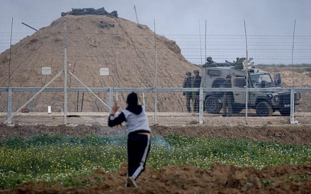 A Palestinian uses a slingshot to hurl objects towards Israeli forces next to an armored vehicle on the other side of the barbed-wire fence, at the border with Israel east of Gaza City on March 1, 2019. (Photo by Said KHATIB / AFP) A Palestinian uses a slingshot to hurl objects towards Israeli forces next to an armored vehicle on the other side of the barbed-wire fence, at the border with Israel east of Gaza City on March 1, 2019. (Photo by Said KHATIB / AFP)