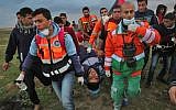 Illustrative: Palestinian paramedics carry away on a stretcher a youth injured during clashes following a demonstration along the border with Israel east of Gaza City on March 1, 2019. (SAID KHATIB / AFP)