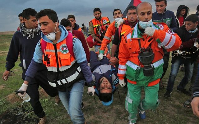 Illustrative: Palestinian paramedics carry away on a stretcher a youth injured during clashes following a demonstration along the border with Israel east of Gaza City on March 1, 2019. (SAID KHATIB / AFP) Illustrative: Palestinian paramedics carry away on a stretcher a youth injured during clashes following a demonstration along the border with Israel east of Gaza City on March 1, 2019. (SAID KHATIB / AFP)