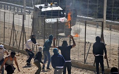 Flames are seen on an Israeli army vehicle after it was hit with a firebomb during clashes with Palestinians in the West Bank village of Beit Sira, west of Ramallah, on March 8, 2019. (Abbas Momani/AFP)