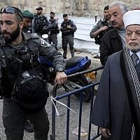 A Border Police officer blocks Grand Mufti Muhammad Ahmad Hussein (L) from entering the Temple Mount compound in the Old City of Jerusalem on March 12, 2019, after it was closed when a firebomb was thrown at police officers. (Ahmad Gharabli/AFP)