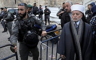 A Border Police officer blocks Grand Mufti Muhammad Ahmad Hussein (L) from entering the Temple Mount compound in the Old City of Jerusalem on March 12, 2019, after it was closed when a firebomb was thrown at police officers. (Ahmad Gharabli/AFP)