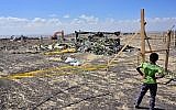 A boy looks as forensic investigators comb the ground for DNA evidence near a pile of twisted airplane debris at the crash site of an Ethiopian airways operated Boeing 737 MAX aircraft on March 16, 2019 at Hama Quntushele village near Bishoftu in Oromia region. (TONY KARUMBA / AFP)