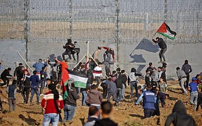 Palestinians wave Palestinian flags as they try to climb the security fence on the border between Israel and the Gaza Strip, east of Gaza City, on March 22, 2019. (Said Khatib/AFP)