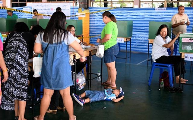 A child lies on the floor as voters cast their ballots at a polling station in Bangkok on March 24, 2019, during Thailand's general election. (Jewel SAMAD / AFP) A child lies on the floor as voters cast their ballots at a polling station in Bangkok on March 24, 2019, during Thailand's general election. (Jewel SAMAD / AFP)